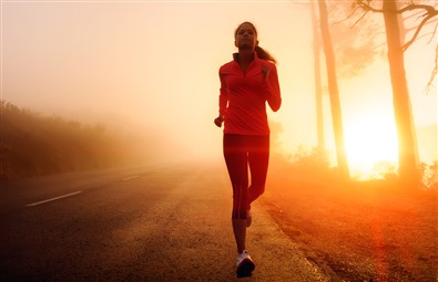 Pige, der jogger ved solopgang.