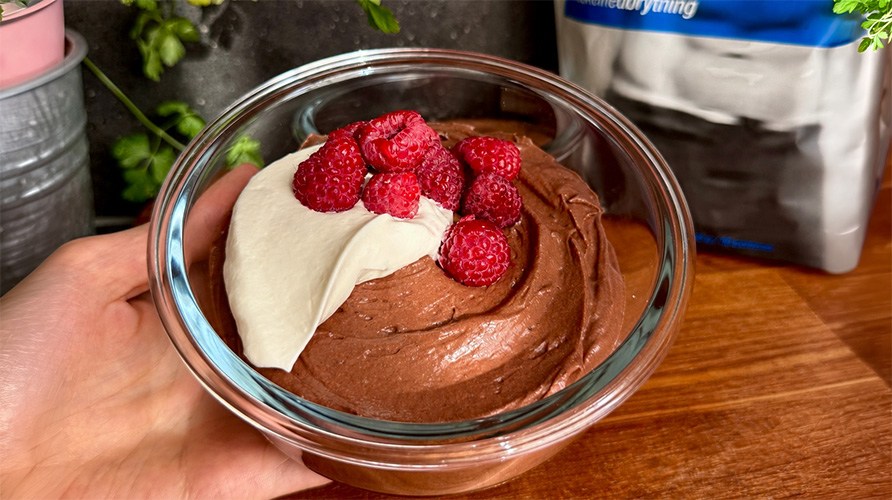 En h�nd holder en sk�l med cremet, proteinrig chokolademousse.
