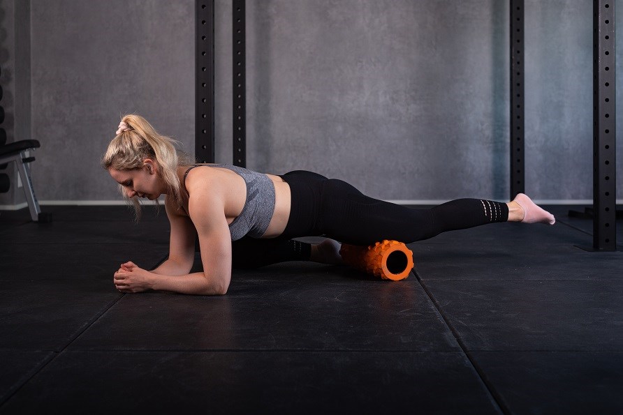 Trnende pige bruger foam roller til benet.