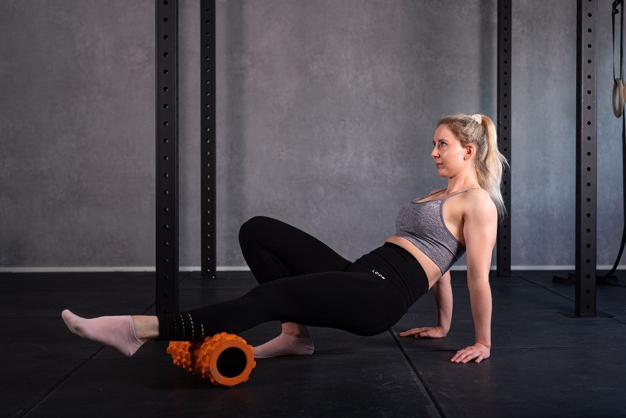 Trnende pige bruger en foam roller til kalvene.