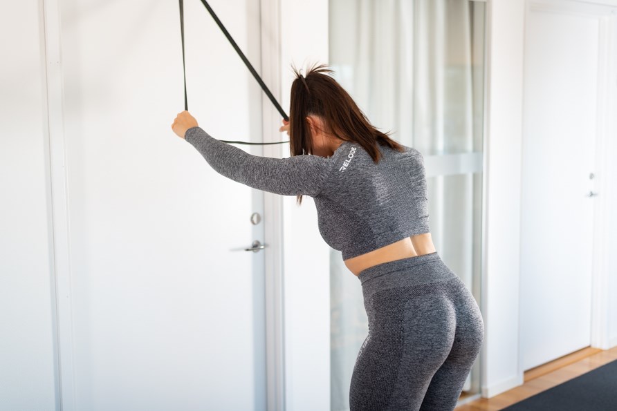 En kvinde skal til at udføre pull downs med en elastik.