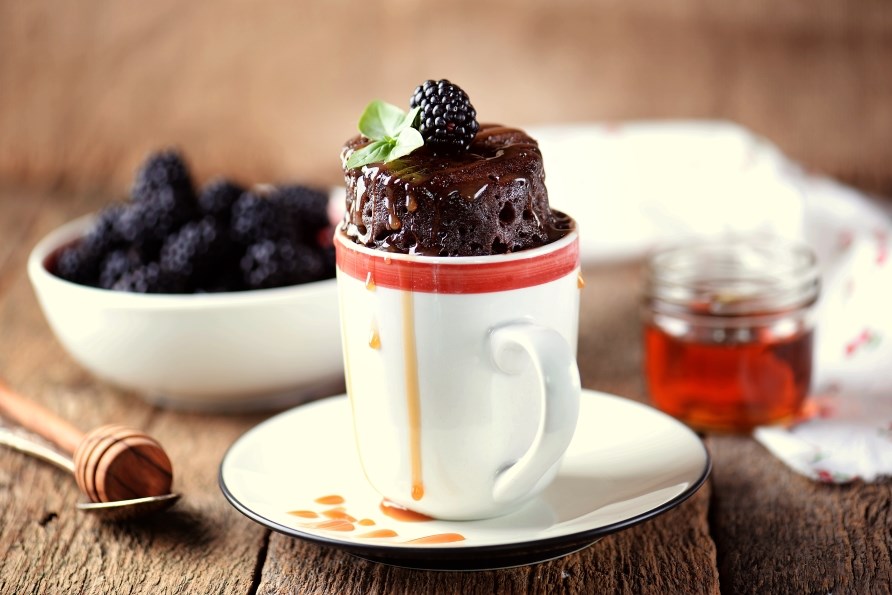 En proteinrig, chokolade mugcake, serveret med friske brombr.