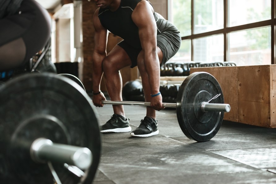 Mand der trner i fitnesscenter med vgtstang.