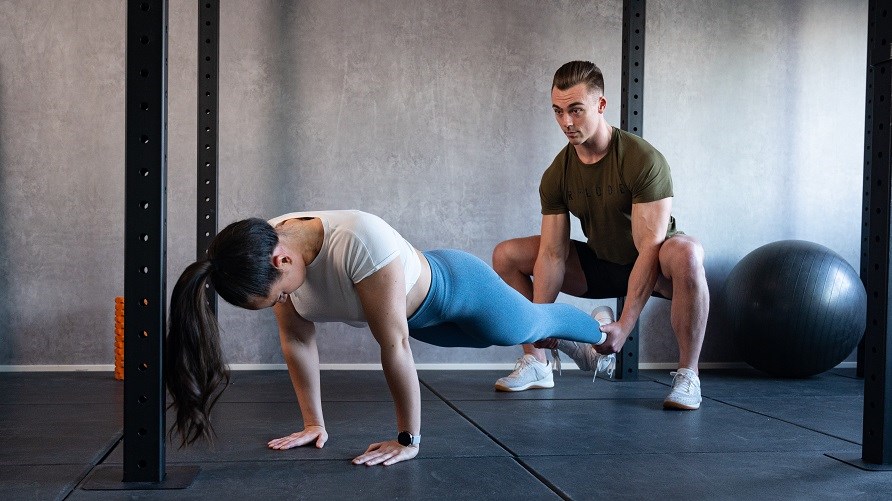 Mand og kvinde laver squat push ups.