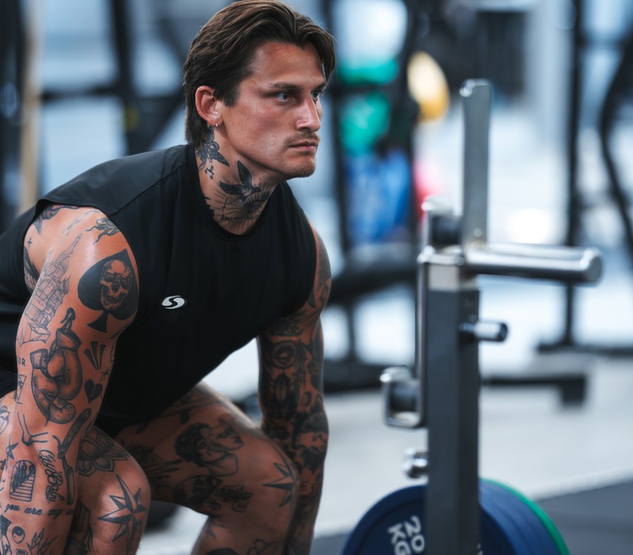 En mand er ved at l�fte en stang med v�gte p�.