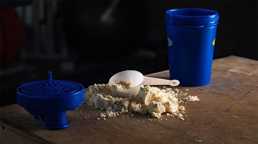 En shaker og en scoop med proteinpulver.