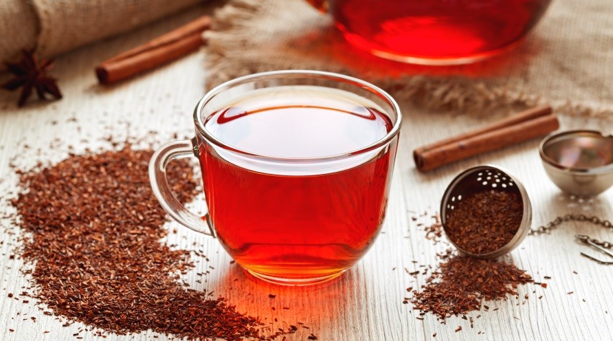 Et krus med rd te, omringet af ls rooibos te.