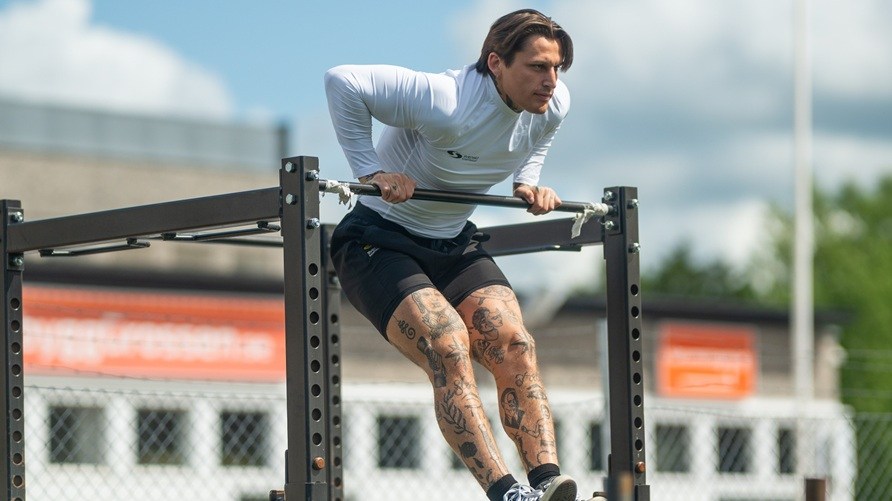Mand, der trner udendrs og laver en muscle-up.