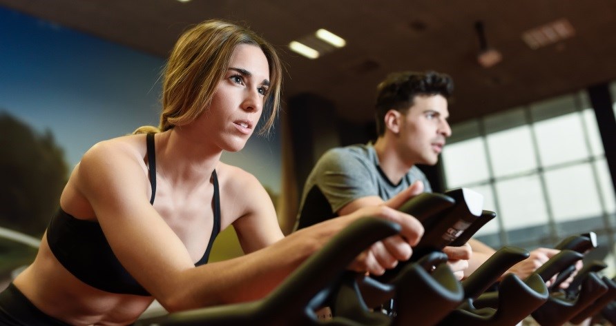 Kvinde og mand sidder på hver deres spinningcykel. Kvinde og mand sidder på hver deres spinningcykel.