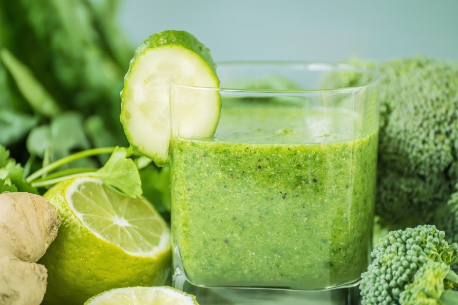 Et glas med grn detox juice, omringet af grnsager.