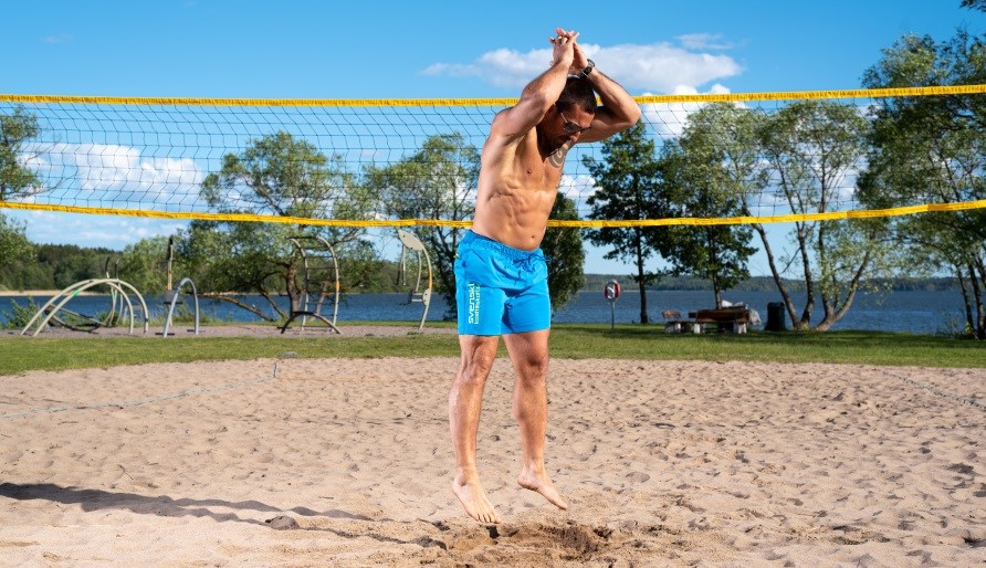 En mand der trner HIIT p en beach volley bane.